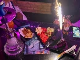 Nightclub table with colorful cocktails, appetizers, and purple ambient lighting